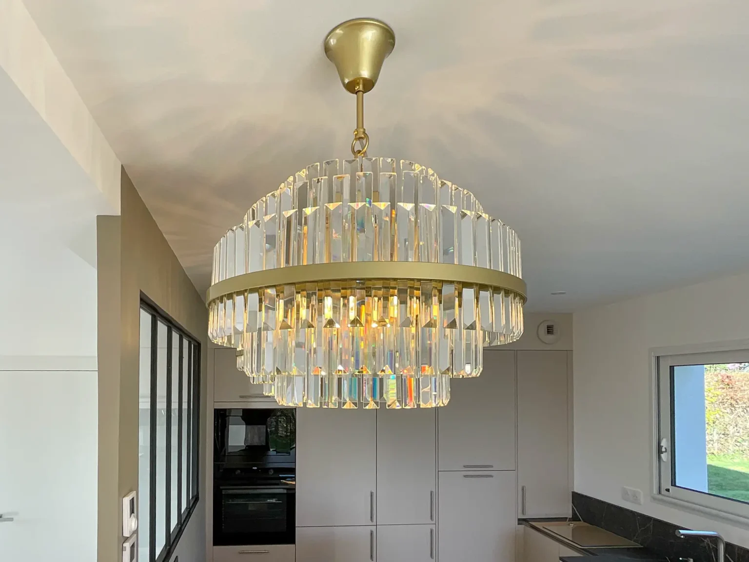 Lustre en cristal à anneaux dorés au-dessus de la cuisine, colonnes de fours encastrés