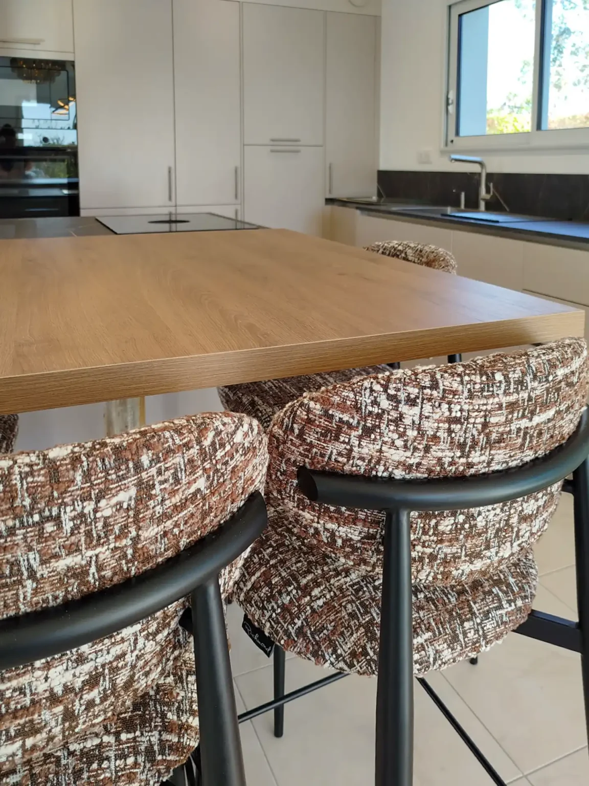 Détail du plateau d'îlot en chêne et des chaises tapissées en tweed, cuisine sur-mesure