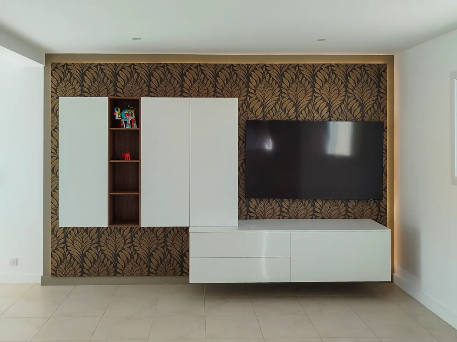Meuble TV suspendu laqué blanc et niche en bois sur papier peint feuillage, salon rénové à Gavrus